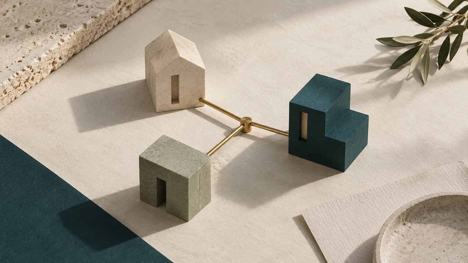 Trois maquettes de bâtiments reliées par des lignes de laiton sur un fond ivoire.